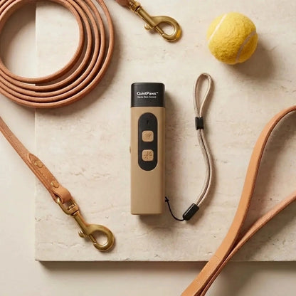 QuietPaws™ Gentle Bark Control device with leashes and a tennis ball on a light surface