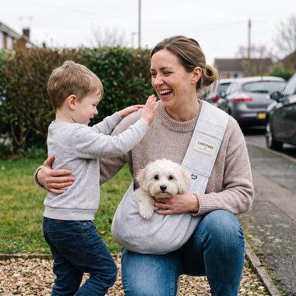 Mother and young son with their small white dog in a light grey CarryPaws dog sling carrier