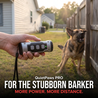 Hand holding the QuietPaws PRO ultrasonic anti-barking device aimed at a German Shepherd barking beside a backyard fence