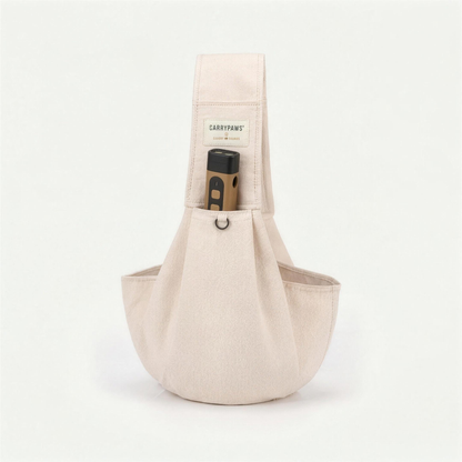 Beige CarryPaws™ dog sling carrier with the brown QuietPaws™ bark control device in its front pocket