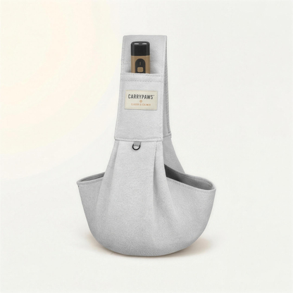 Light grey CarryPaws™ dog sling carrier with the brown QuietPaws™ bark control device in its front pocket